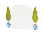 Two tall, green topiary trees in blue-and-white pots frame a blank arched white backdrop—ideal for displaying the Hester & Cook Floral Place Card Collection at your table setting.