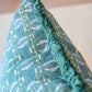 Close-up of the Associated Design Teal Sicily Outdoor Pillow, featuring a white bird pattern and green fringe trim, expertly crafted for a touch of luxury in your home.