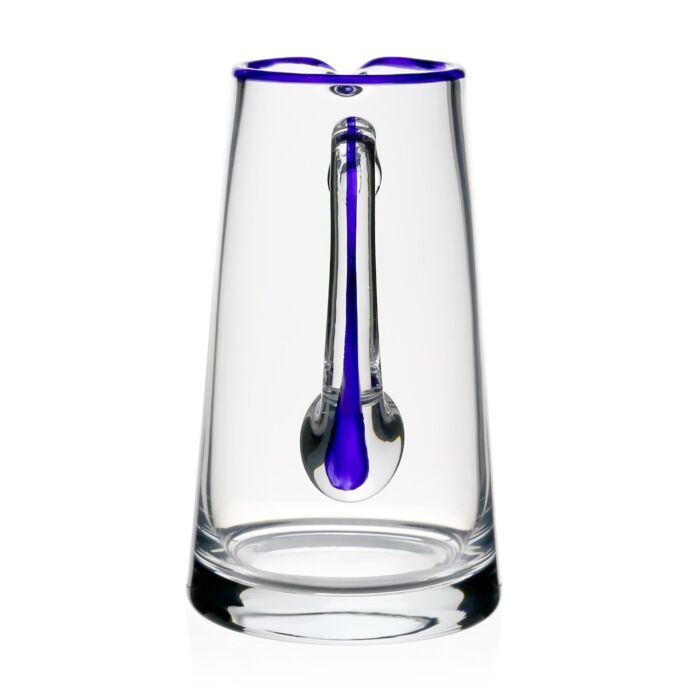 The William Yeoward Crystal Siena Pitcher Collection features clear glass with a vibrant blue rim and an elongated blue element, shown on a white background. Proposition 65 warning applies.