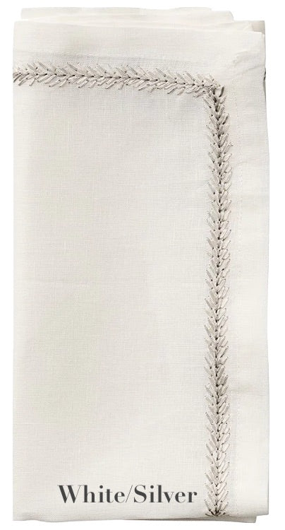 A folded white linen napkin with silver embroidery along the edge, labeled "White/Silver" at the bottom, from Kim Seybert's Jardin Napkin Set.