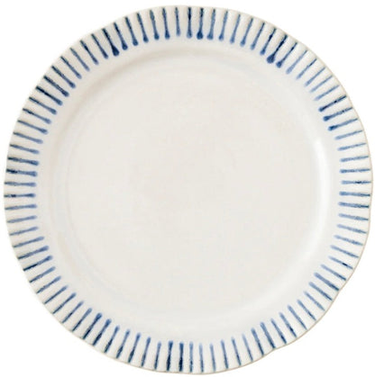 A white ceramic plate from Juliska's Sitio Stripe Delft Blue Dinnerware Collection displays a scalloped edge and radiant blue rim stripes, seen from above.