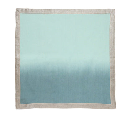 A Kim Seybert Dip Dye Napkin from the Dip Dye Napkin Set, featuring a hand-dipped light blue and teal ombre center with a beige border, is laid flat on a white background.