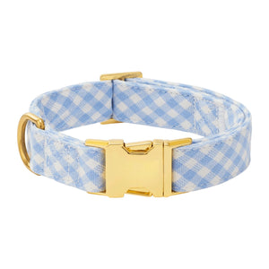 The Foggy Dog Sky Blue Gingham Spring Dog Collar features a gold-toned metal buckle and D-ring, displayed on a white background.
