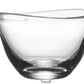 A small clear glass bowl from the Barre Bowl Collection by Simon Pearce, featuring a contemporary rounded shape with an asymmetrical wave along its slanted rim, displayed on a white background with the word "Small" below.