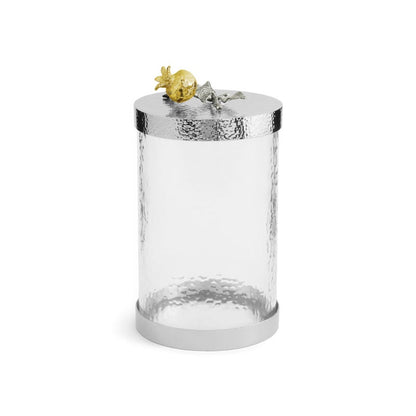 The Michael Aram Pomegranate Silver & Gold Canister features a clear cylindrical glass jar with a silver-toned hammered metal lid and a gold-silver pomegranate accent, inspired by ancient motifs from the Pomegranate Collection.
