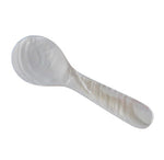 The Be Home Small Seashell Spoon features a rounded bowl and short, flat handle. Ethically sourced and handcrafted by women artisans, it is shown against a white background.