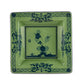 The Oriente Italiano Malachite Dinnerware Collection by Ginori 1735 features green ceramic plates inspired by Faenza ceramics, with dark blue floral and geometric borders and central floral motifs.