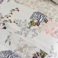 The Naiades Bedding Collection by Yves Delorme showcases bed linens in vibrant floral and botanical prints on white organic cotton, including a reversible duvet cover.
