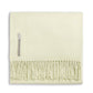 The Alicia Adams Alpaca Classic Throw Collection features a folded pale yellow baby alpaca blanket with fringe and a fabric label, fair-trade made in Peru—a soft, luxurious accent for any space.