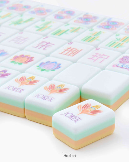 The Oh My Mahjong Mahjong Tile Collection features pastel, hand-painted tiles with floral designs and "JOKER" text, arranged in neat rows for a refined gaming experience.