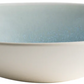 From the Vuelta Ocean Blue Collection by Jars, this shallow round ceramic bowl features a white exterior and light blue ocean glaze interior, radiating timeless elegance against a white background.