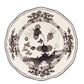 A round ceramic plate with a scalloped edge, showcasing a black and white floral and landscape motif from the Oriente Italiano Albus Dinnerware Collection by Ginori 1735.