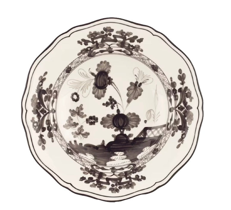 A round ceramic plate with a scalloped edge, showcasing a black and white floral and landscape motif from the Oriente Italiano Albus Dinnerware Collection by Ginori 1735.