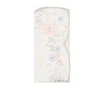 The Printemps Napkin Set by Kim Seybert features folded white napkins with embroidered pastel flowers and gold-trimmed scalloped edges, inspired by the brand’s signature floral designs.