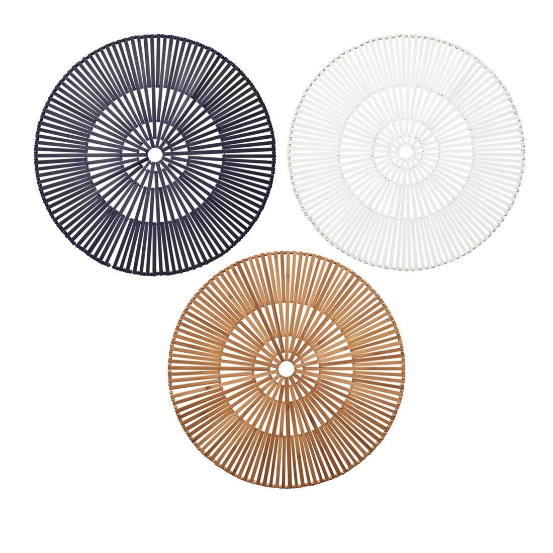 Three Kim Seybert Spoke Placemats, including a white version, are displayed in a triangular formation on a white background, blending organic elements with subtle geometric patterns.