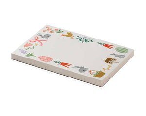 The Spring Farm Notepad by Rifle Paper Co. features rabbits, flowers, carrots, eggs, a basket, house, and hen around a white border—perfect for daily notes with easy tear-off sheets.