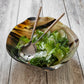 A vibrant green salad with lettuce, kale, and cucumber is beautifully served using Be Home’s Aquila Serving Collection on a rustic wooden surface.