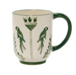 Johanna Ortiz’s Casa Dark Jungle Dinnerware Collection features a white ceramic mug with a green handle, adorned with parrot and leaf designs—perfect for adding charm to any mix-and-match tablescape.