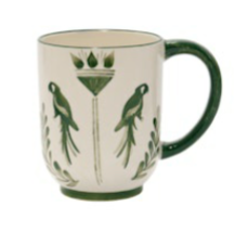 Johanna Ortiz’s Casa Dark Jungle Dinnerware Collection features a white ceramic mug with a green handle, adorned with parrot and leaf designs—perfect for adding charm to any mix-and-match tablescape.