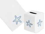 The Haute Home Playful Starfish Bath Collection in Blue includes a white Italian linen tissue box cover and matching towel, both hand-embroidered with charming blue starfish designs.