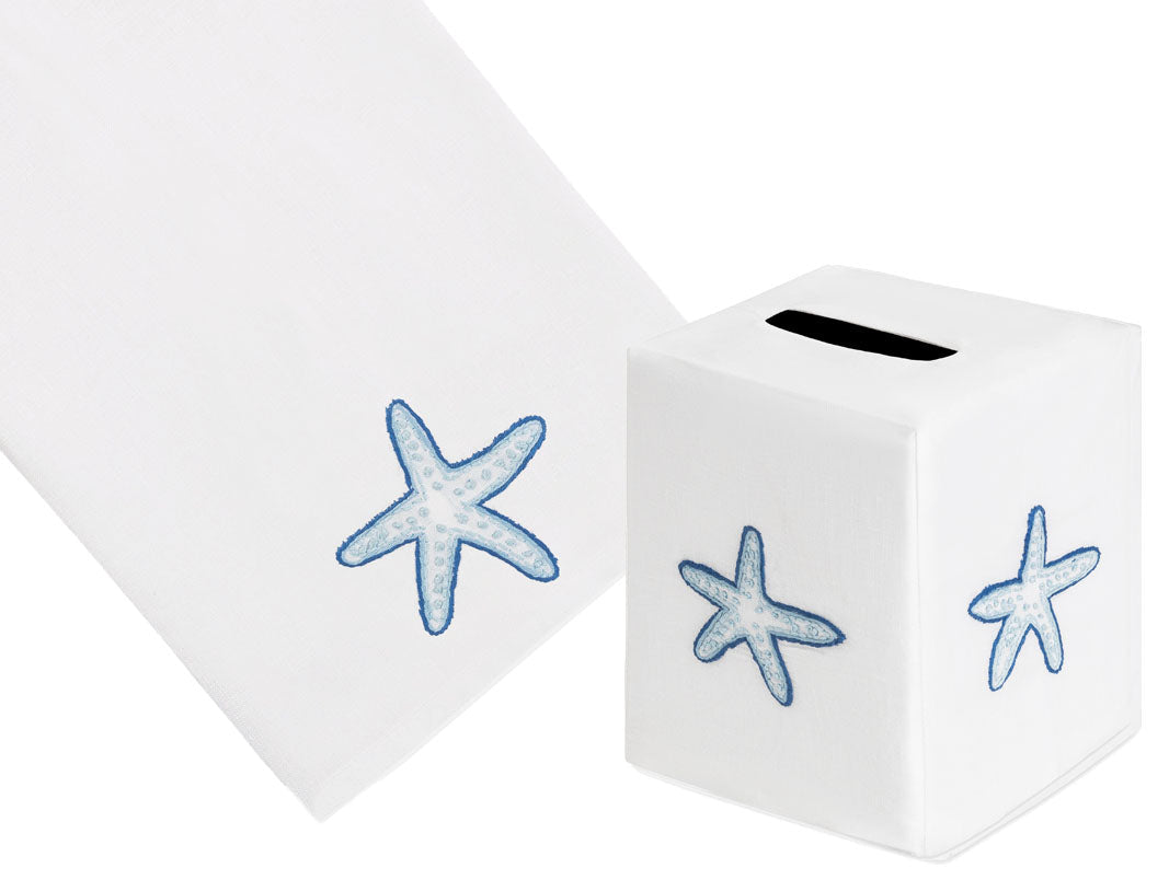 The Haute Home Playful Starfish Bath Collection in Blue includes a white Italian linen tissue box cover and matching towel, both hand-embroidered with charming blue starfish designs.