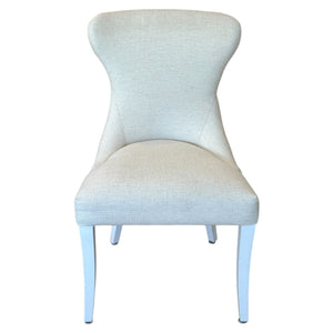 The Lee Industries Curved Back Dining Chair is a beige, upholstered chair with a sophisticated style and four white legs, shown front-facing against a white background.