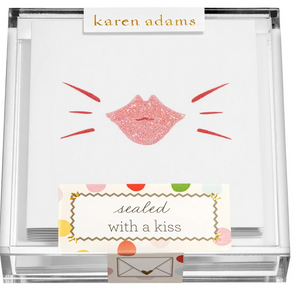 The Kiss Gift Enclosure Set by Karen Adams features hand-glittered cards with a pink glittery lip print, packaged in a clear box labeled "sealed with a kiss" above an envelope, perfect for charming gift enclosures.