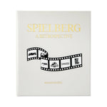 The white cover of "Steven Spielberg: A Retrospective" by Graphic Image features a film strip with logos from Jaws, E.T., Jurassic Park, Schindler’s List, and West Side Story—celebrating Spielberg’s iconic career.