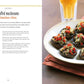 Six stuffed mushroom caps, topped with chopped red peppers, are artfully presented on a dark plate beside a glass of light-colored beverage—the perfect Spanish appetizer from the “Tapas” collection by Simon & Schuster, as shown on the left.