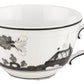 The Oriente Italiano Albus Dinnerware Collection teacup by Ginori 1735 is made of fine white porcelain, adorned with a black floral and geometric pattern, a curved handle, and accented with a thin black line at the rim.