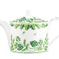 The Cobblers Cove Calypso Dinnerware Collection by Royal Crown Derby features a white ceramic teapot with a round lid and green leaf and vine motifs, evoking a Caribbean feel and pairing perfectly with vibrant green tableware.