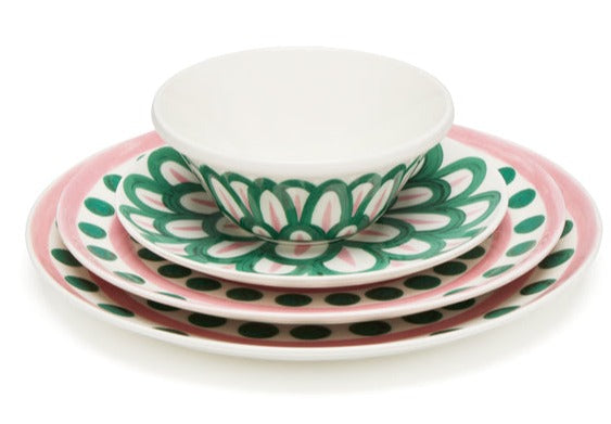 A stack of decorative plates and a bowl from the Themis Z Symi Green and Pink Collection, with pink edges and green floral patterns on a white background.