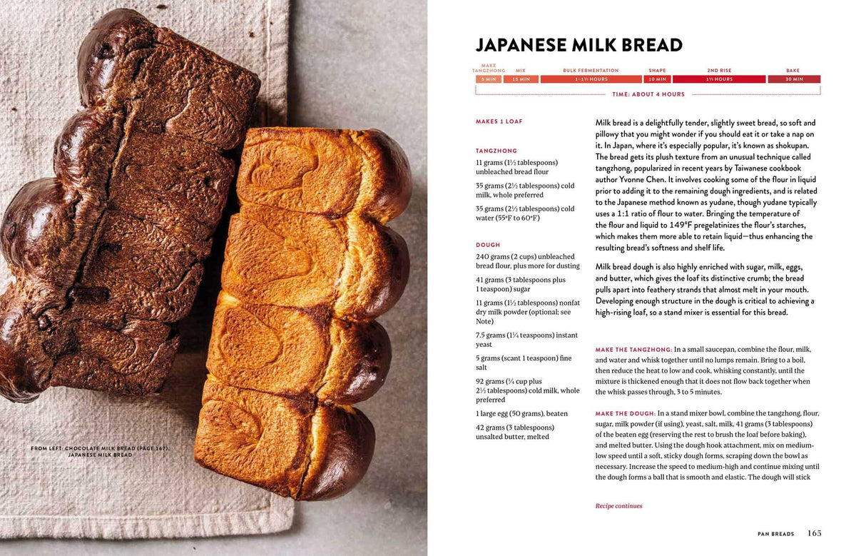 Two loaves of Japanese milk bread—one plain and one marbled with chocolate—sit side by side on a beige surface next to the open King Arthur Baking Company Big Book of Bread from Simon & Schuster, inviting you to discover new bread recipes inspired by its expert guidance.