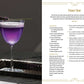 A vibrant purple mocktail from Mocktail Club by Simon & Schuster is elegantly served in a coupe glass and garnished with a sprig of lavender, presented on a black tray with an additional lavender sprig atop a dark surface—an ideal creative beverage for any occasion.