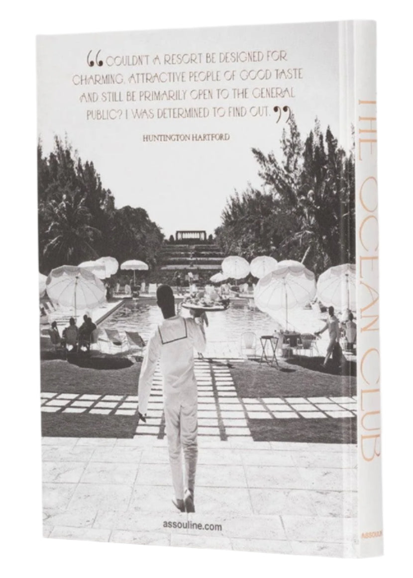 A person in a white outfit stands poolside at a luxury resort, echoing Bond movies' style. The setting includes lounge chairs, umbrellas, and palm trees, mirroring the serene elegance of Assouline's The Ocean Club in the Bahamas.