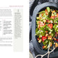 An open cookbook titled “Salad Lab: Whisk, Toss, Enjoy!” by Simon & Schuster displays a vibrant spinach salad recipe on the left page and a platter brimming with colorful spinach salad featuring strawberries, nuts, and cheese on the right—all presented with serving tongs atop a dark surface, reminiscent of The Salad Lab’s viral creations seen on TikTok.