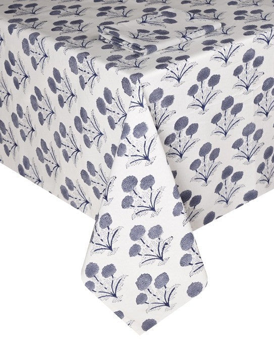 A white tablecloth from the SLOANE BY HAND Poppy Table Linen Collection showcases blue floral clusters in a hand block print-inspired pattern, elegantly draped over a rectangular table.