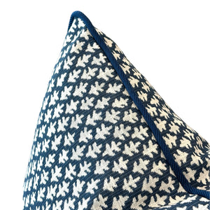 Close-up of the Burma Indigo Outdoor Pillow by Associated Design, featuring a navy blue and white pattern with blue piped edges, expertly crafted from premium materials, displayed against a white background.
