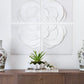 A wooden sideboard with decorative items, including two ornate vases and a small plant in a white ceramic pot, is situated below four pieces of large, 24" square White Flower Quadrant wall art by Tommy Mitchell.