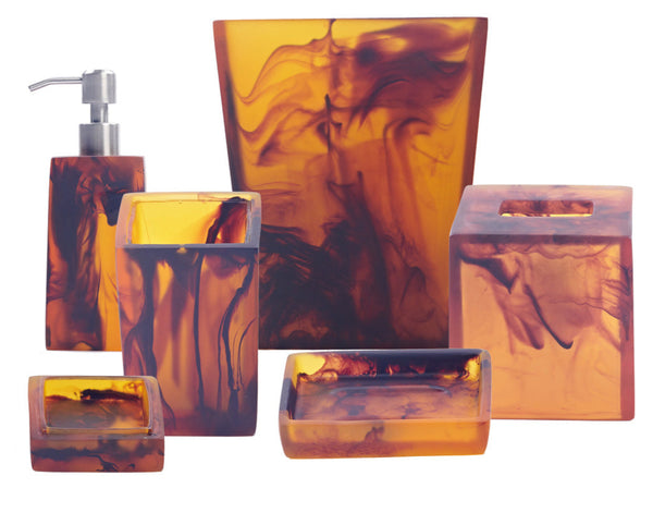 Nashi Home's Tortoise Bath Collection includes vibrant amber and black swirled accessories crafted from Nashi resin, featuring a soap dispenser, tumblers, tissue box, and trays.