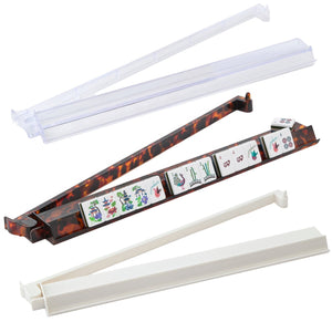 The Oh My Mahjong Acrylic Mahjong Rack and Pusher Set includes three racks—tortoiseshell, white, and clear—each with tile slots in a row. Some racks feature integrated pushers for easy gameplay.