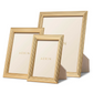 The Alessio Frame Collection by Aerin showcases three rectangular gold frames of assorted sizes with a classic reeded design, standing upright on a white background—perfect for elegantly displaying photographs.