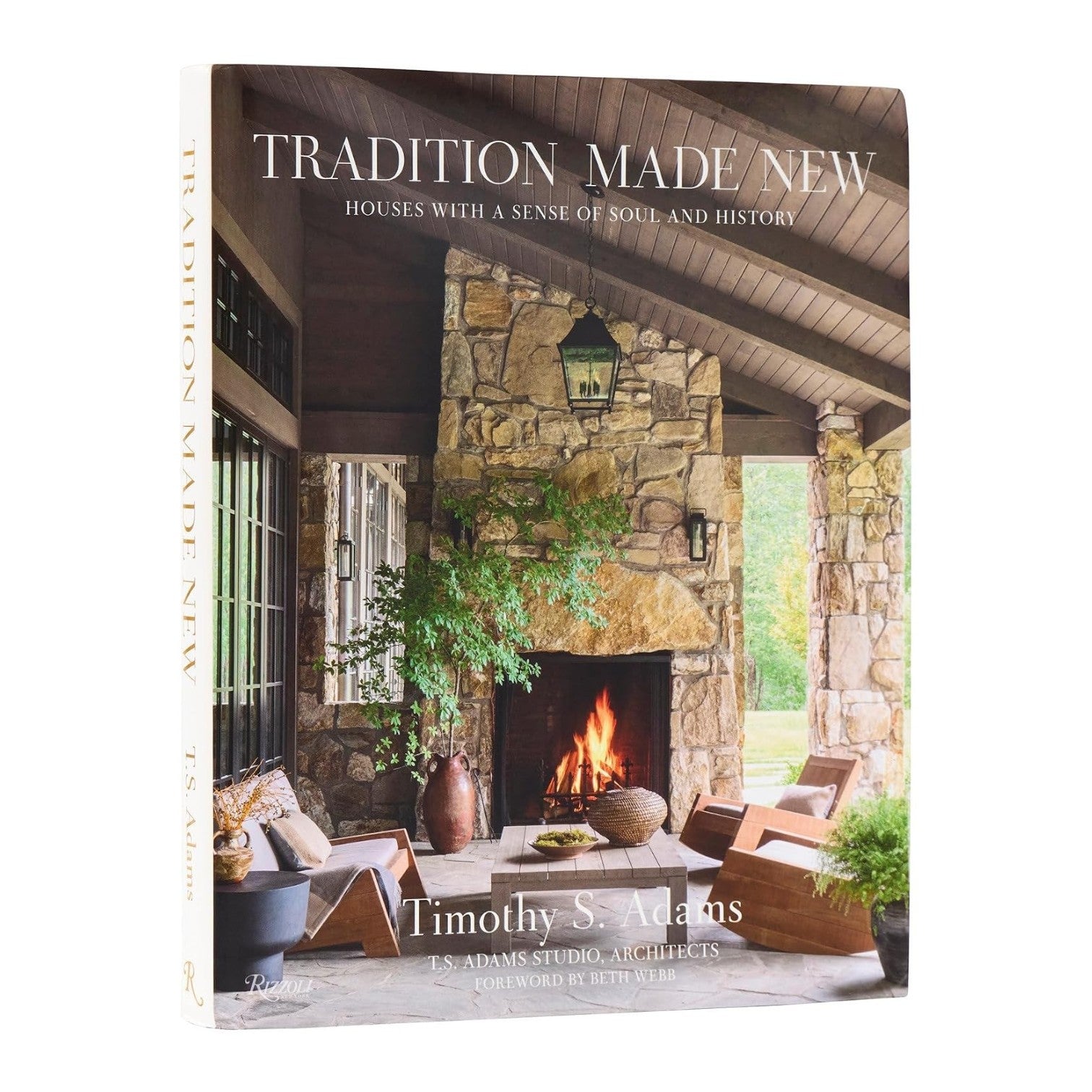 The “Tradition Made New” book from Penguin Random House stands upright, its cover displaying a rustic stone fireplace and cozy seating—an inviting presentation of natural materials that underscores architect Timothy S. Adams’s commitment to timeless craftsmanship.