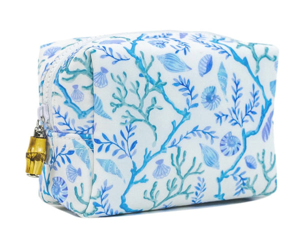 The TRVL Design TRVL Bag, Coral Vine, is a white zippered pouch with blue and teal marine-themed illustrations of seaweed and shells, ideal for toiletries. It features a chic gold zipper pull.