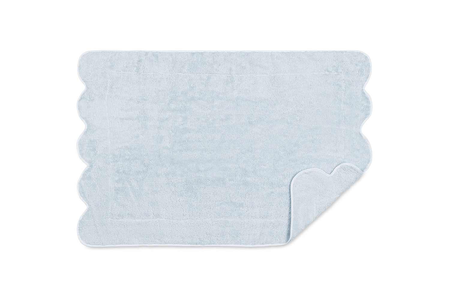 The Matouk Cairo Scallop Bath Collection features a light blue rectangular bath mat with scalloped edges, shown on a white background with a corner flipped to display the underside, pairing beautifully with our luxury bath towels.