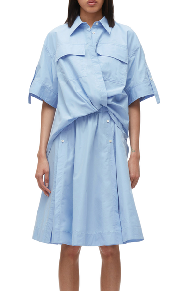 A person in a blue 3.1 Phillip Lim Tucked Front Shirt Dress with short sleeves and a tie waist, designed with an oversized fit.