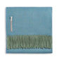 The Alicia Adams Alpaca Classic Herringbone Throw Collection features a folded blue herringbone-patterned baby alpaca blanket with a green fringe and fabric label, fair-trade crafted in Peru.