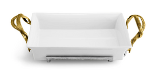 The Michael Aram Palm 2-Quart Casserole Dish features a rectangular white ceramic dish with antique gold-finished handles and a silver metal base inspired by woven palm leaves, set against a white background.