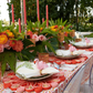 A decorated outdoor table features floral centerpieces, pink candles, gold-rimmed glasses, and plates with napkins topped by the Kim Seybert Aruba Napkin Ring in Blush.