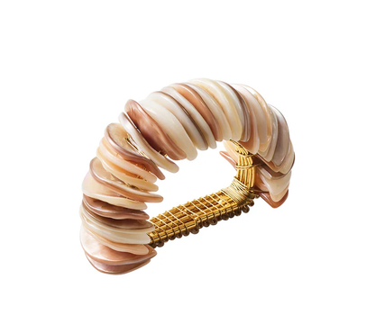 The Kim Seybert Shell Arch Napkin Ring features layered oval mother-of-pearl pieces and a gold-toned woven metal band, shown on a white background.